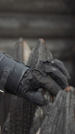 black knight hand rests on spiky wooden fence. evil warrior strikes ground with spear angrily waiting for opponent to come to duel closeup on blurred background