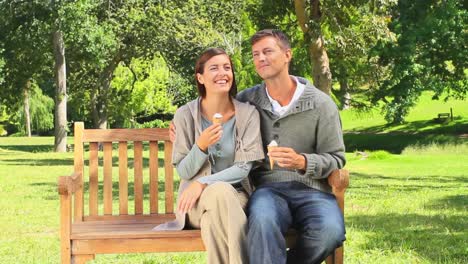 Young-couple-eating-icecream-on-a-public-bench