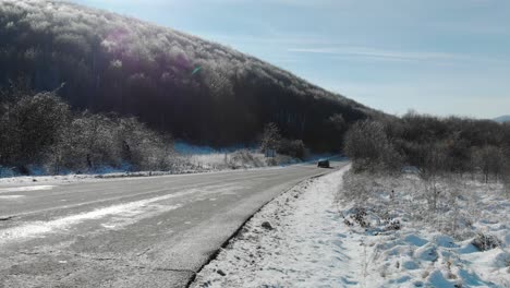 Amplia-Toma-De-Un-Coche-Que-Pasa-Y-Desaparece-En-El-Día-De-Invierno,-Camino-Seco-Y-Fondo-Nevado