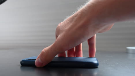 a phone user puts his mobile upside down on the table to stay focused and not get distracted