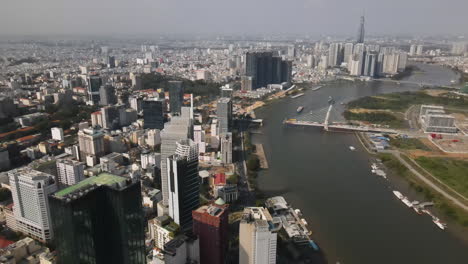 aerial view of modern ho chi minh cityscape, riverside buildings and towers on sunny day, establishing drone shot