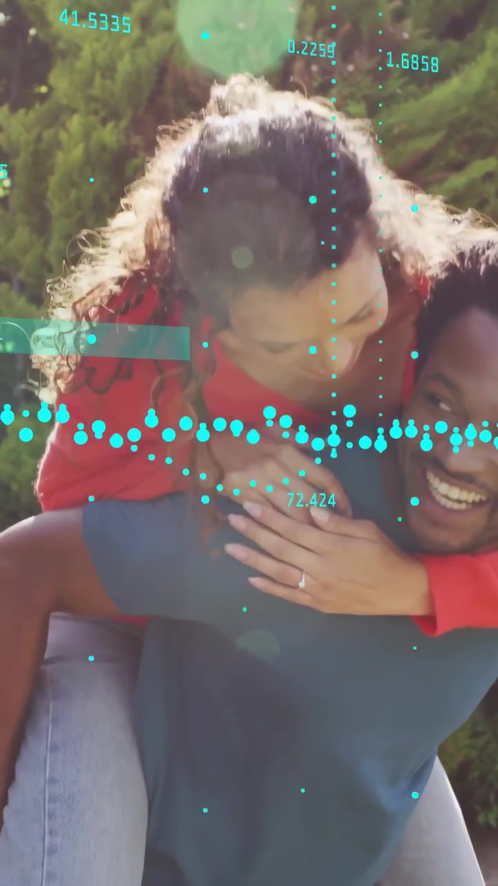 Video verticale: Donna che salta sulla schiena di un uomo giocando in un giardino soleggiato, con un overlay tecnologico che traccia un anello.