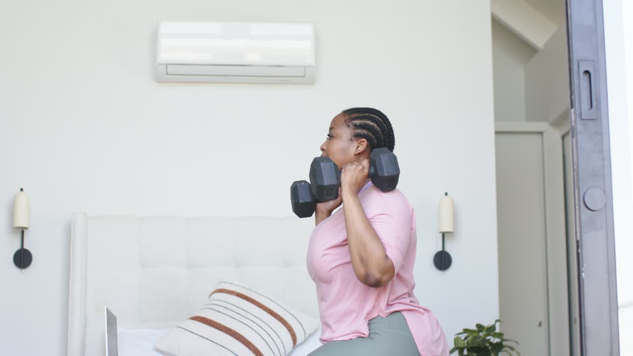Holding hex dumbbells at shoulder level, woman is stepping into deep lunges for home workout