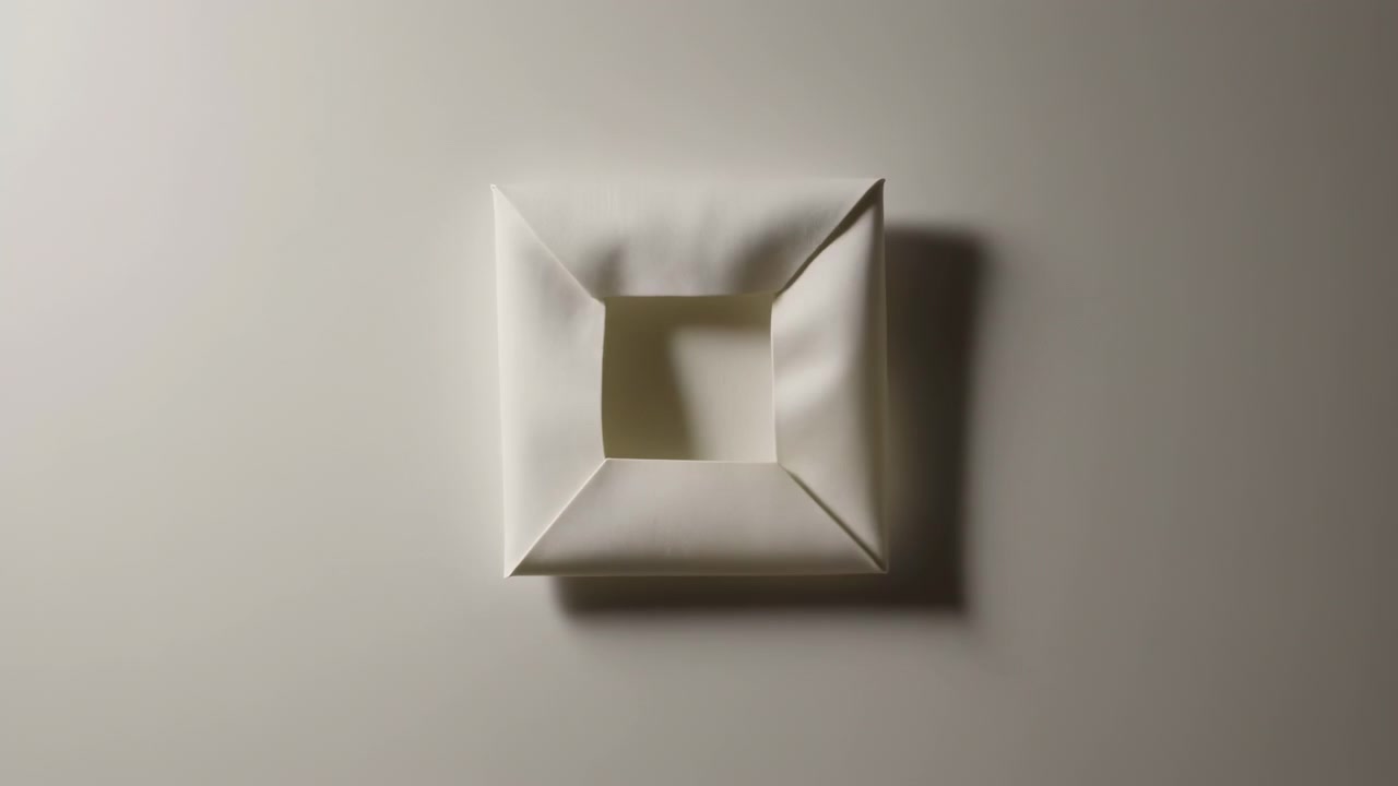 Linen canvas transforms from flat stretched panel into compact folded square against warm gray neutral wall, revealing mitered corners, creases, depth, shadow, and tactile fabric detail