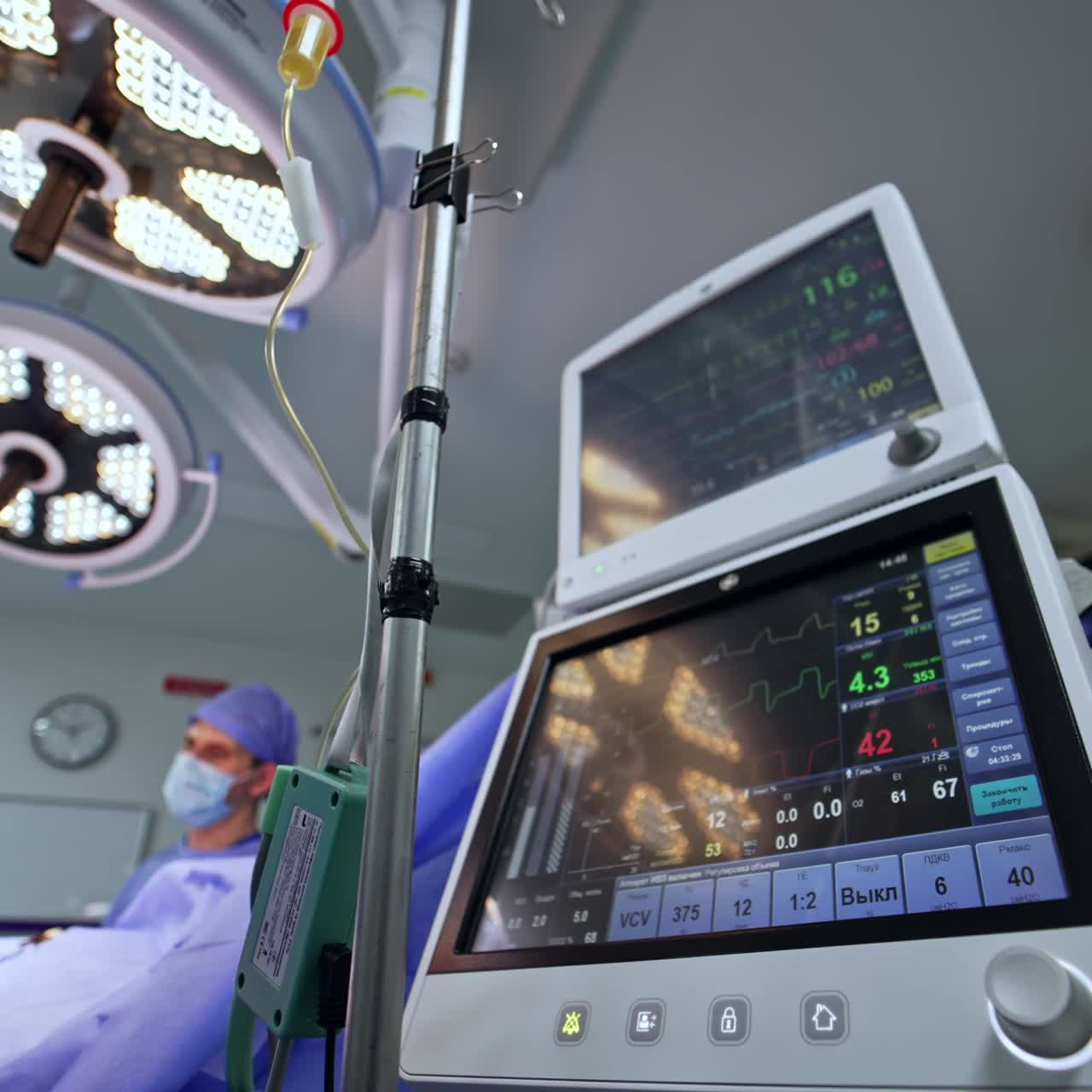 Modern medical equipment for surgical rooms working during operation. Screens of artificial lung ventilators with life signs. Doctors perform neurosurgery. Low angle view