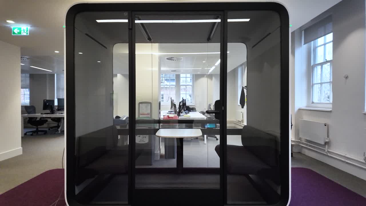 Comfortable workplace in soundproof booth with glass walls for privacy and concentration in shared office space