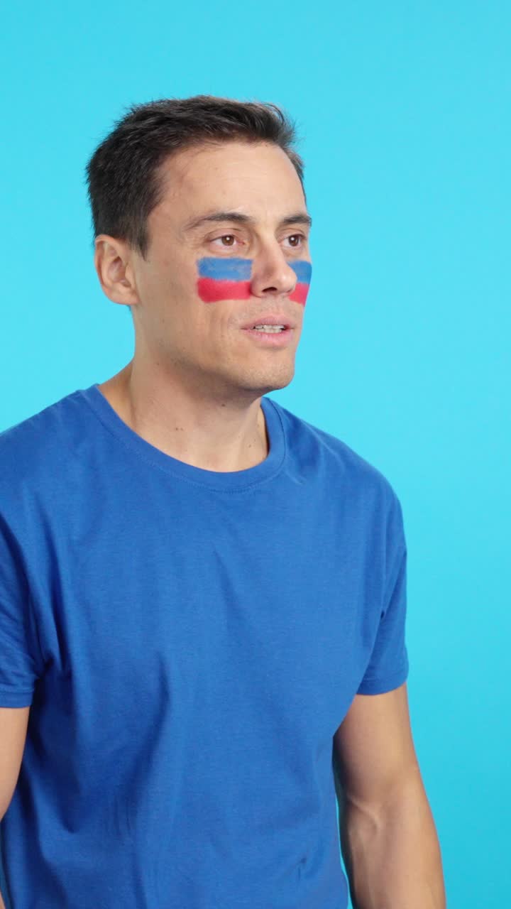 Happy man with haitian flag painted on face looking away