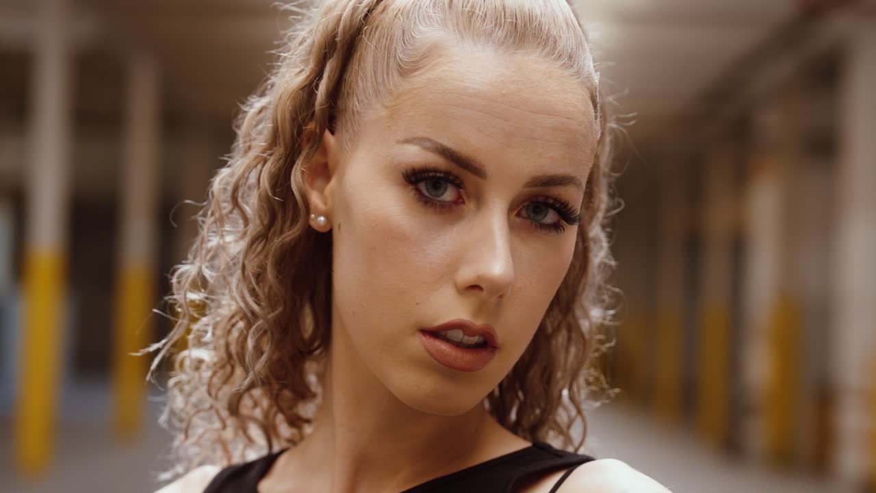 Tattooed woman in industrial hall looking over shoulder – camera moves in slowly