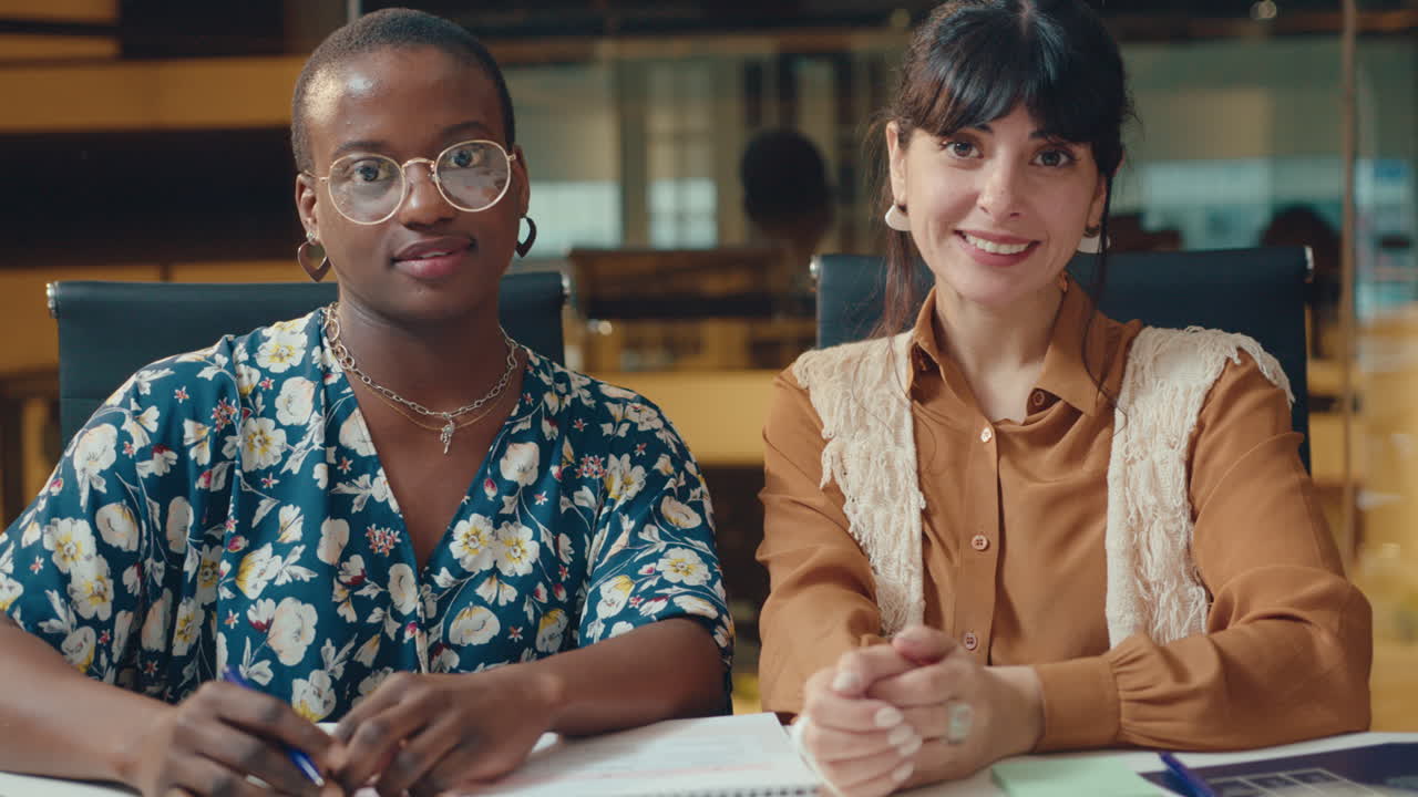 dos jóvenes mujeres de negocios posando para la cámara en el escritorio de la oficina