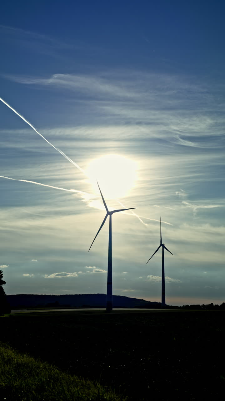 Grandes turbinas eólicas giram ao pôr do sol. Aerogeradores no campo contra o céu. Produção de energia verde por aerogeradores.
