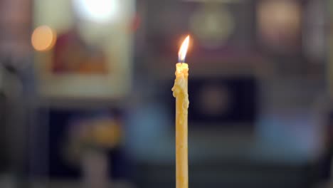 focus pull handheld shot of a melting yellow candle