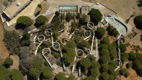 viejo parque acuático oxidado con toboganes de agua y piscina podrida durante el día soleado, tiro aéreo de pájaros descendientes