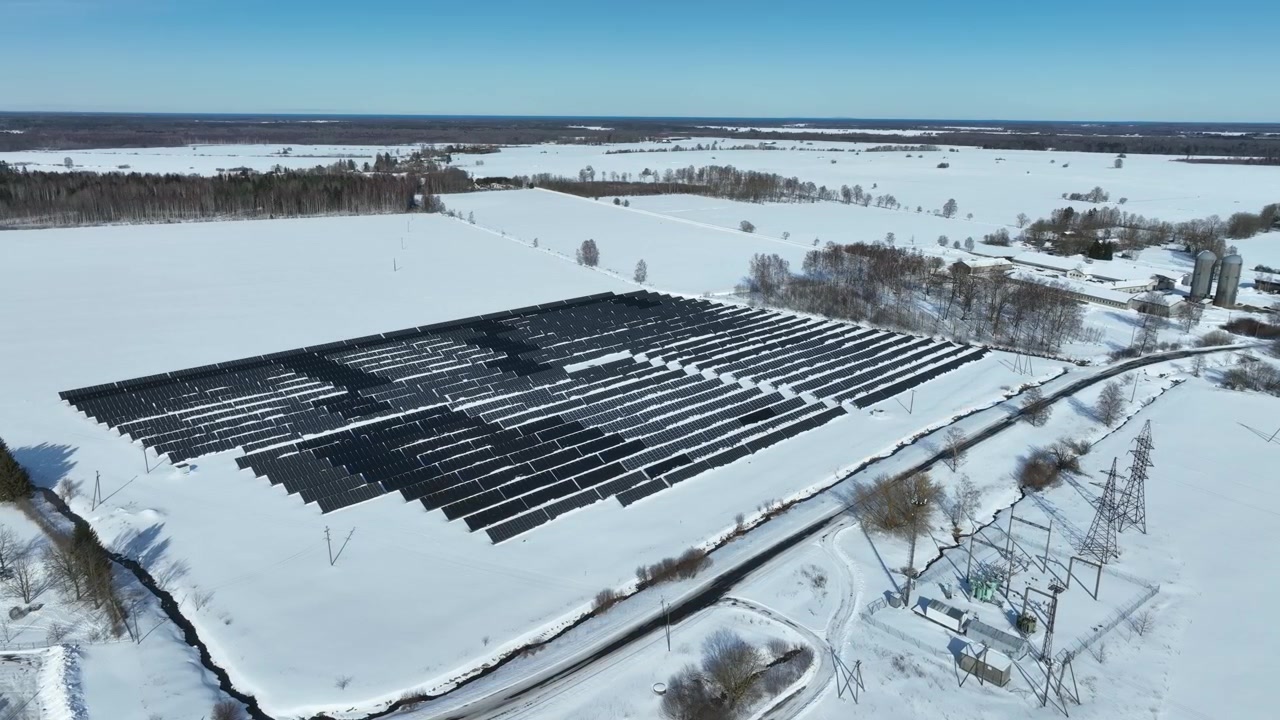 Rotující letecký pohled dronu na panely solární elektrárny v řadě na zasněžených polích. Haljala, Estonsko