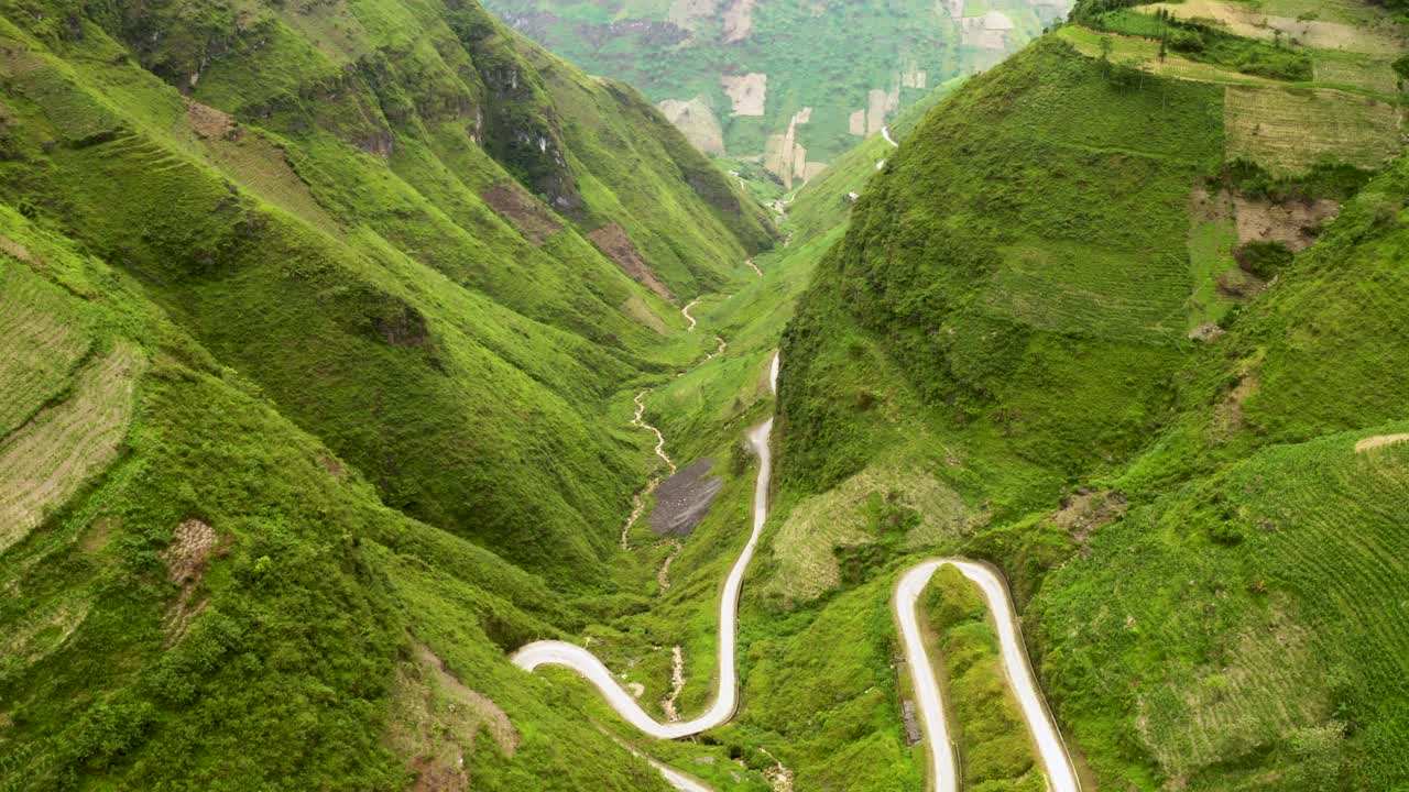 vista de arriba hacia abajo de una preciosa carretera sinuosa tallada en un empinado y exuberante valle verde en las montañas del norte de vietnam
