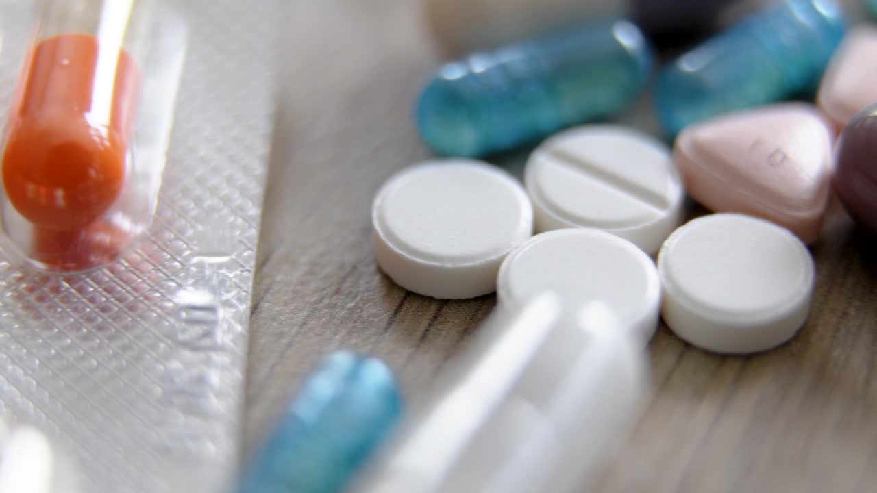 variety of capsules and tablets on wooden surface in medical slide shot with soft focus