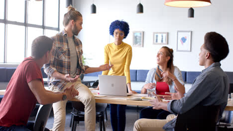 Happy-diverse-business-creatives-using-laptop-in-discussion-in-casual-office-meeting,-slow-motion