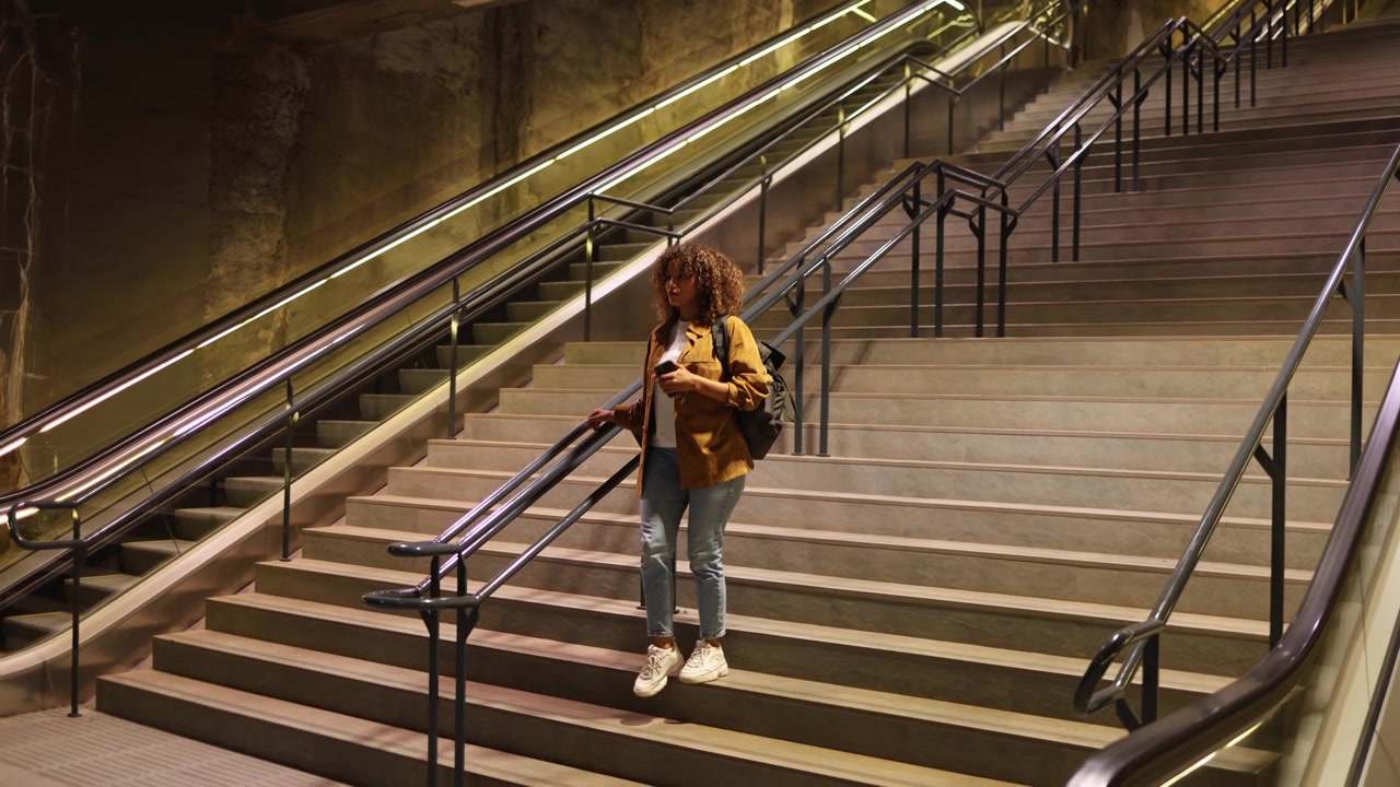 Ung kvinde går ned ad lange trapper på en moderne metrostation