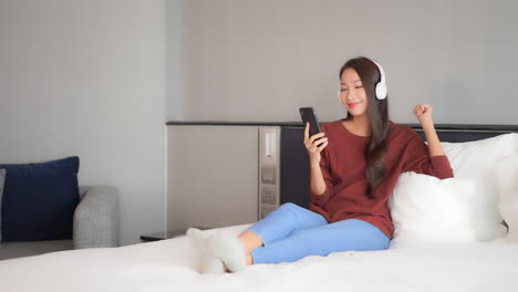 attractive young lady listening to relaxing music on her wireless headphones from a mobile app or radio