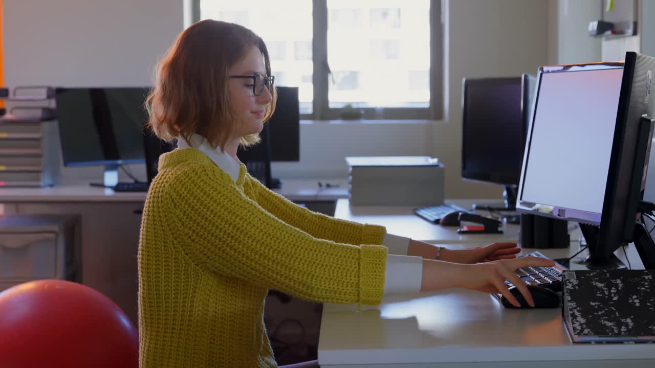 vista lateral de una joven ejecutiva caucásica que trabaja en un escritorio en una oficina moderna 4k