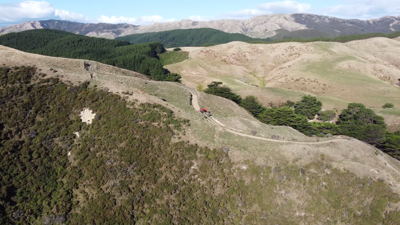 una toma en órbita lenta de una excavadora haciendo un camino hacia un parque eólico