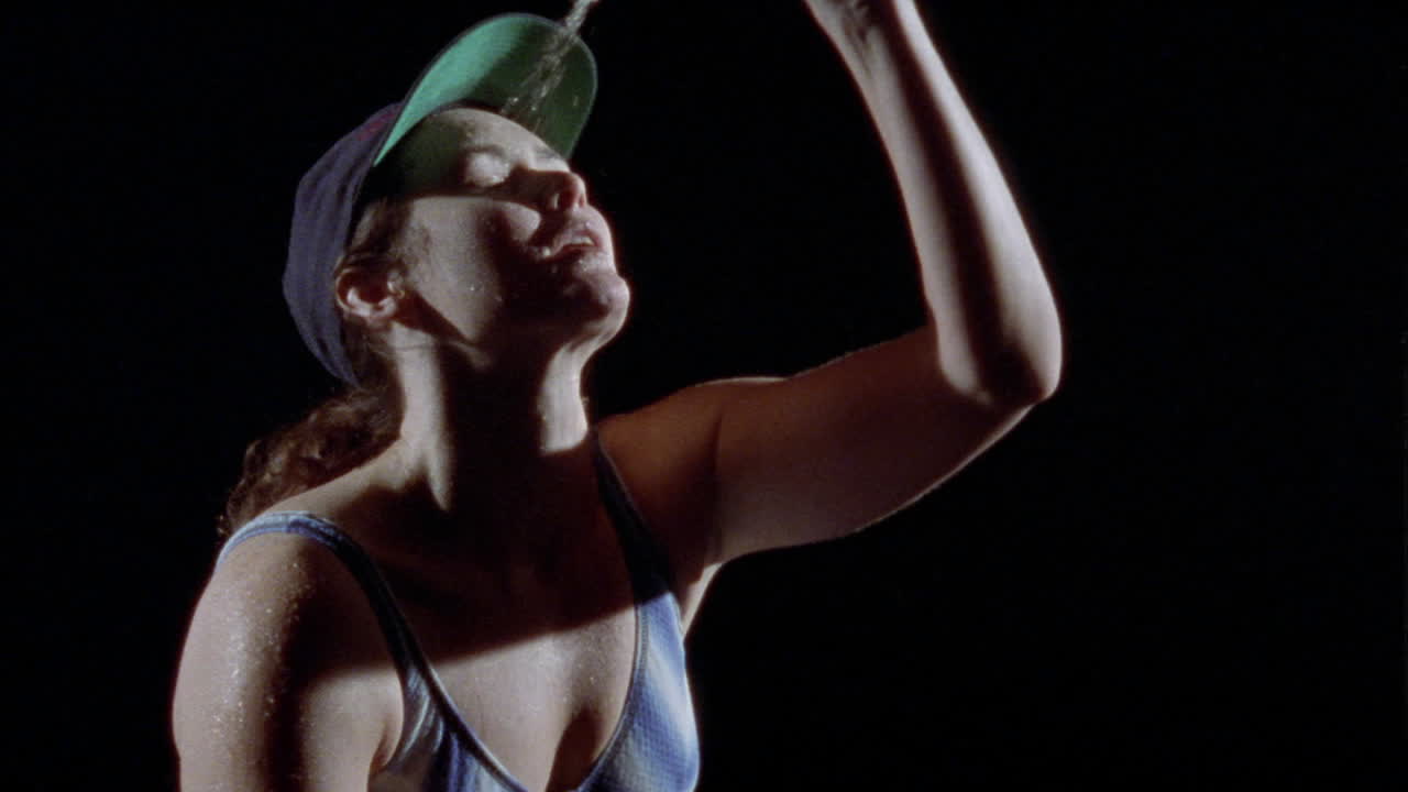 una mujer se vierte agua de una botella en la cara