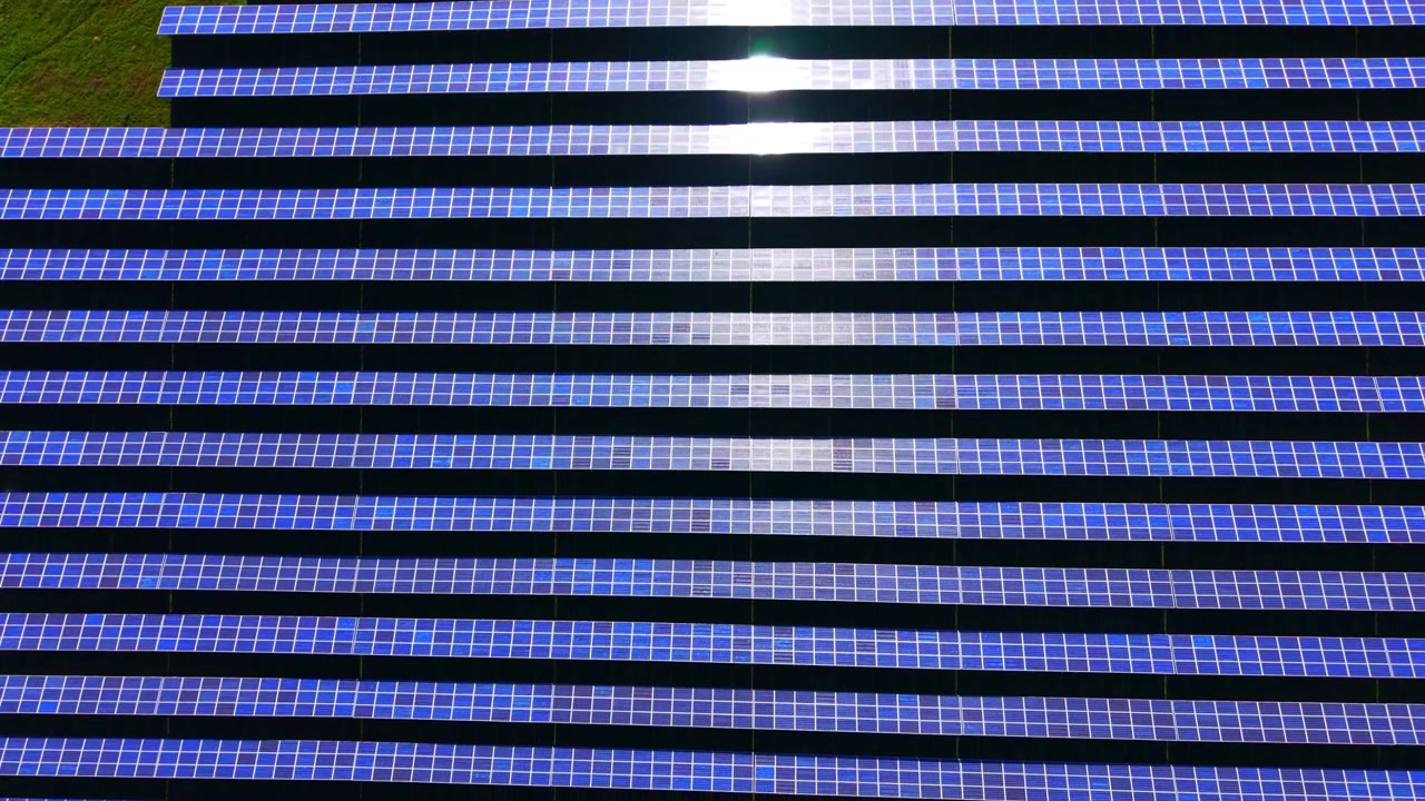 Molteplici file orizzontali fotovoltaiche che mostrano un forte bagliore bianco in una giornata di sole. Array di pannelli solari per energia pulita sotto la luce solare intensa.