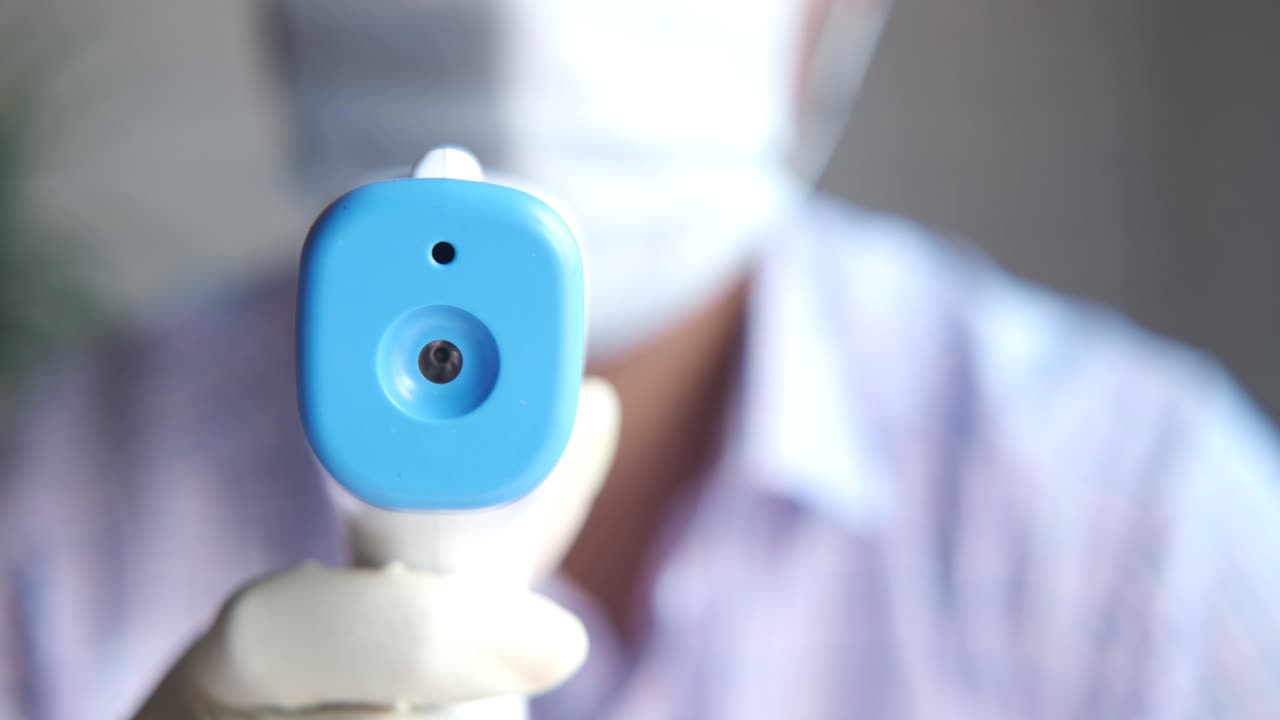 Person taking temperature with infrared thermometer