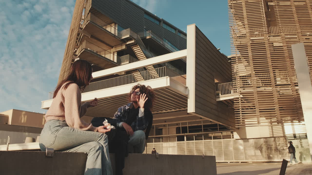 Two women sitting in front of a modern building