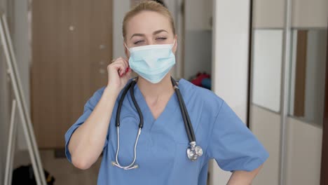 medical practitioner in mask adjusting stethoscope