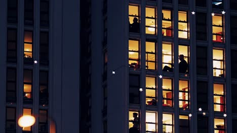 apartment building at night with lit windows and people