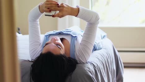 mujer hermosa usando teléfono móvil mientras se relaja en la cama 4k