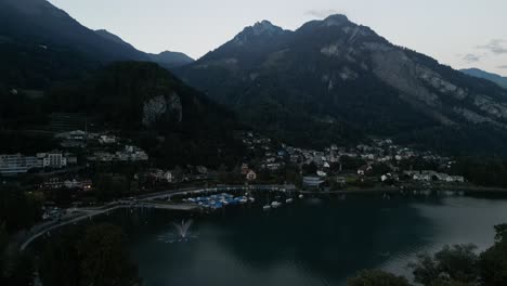 Luftaufnahme-Des-Sees-Im-Tal-Rund-Um-Die-Hohen-Berggipfel-Mit-Springbrunnen-Und-Vielen-Wassersportmöglichkeiten