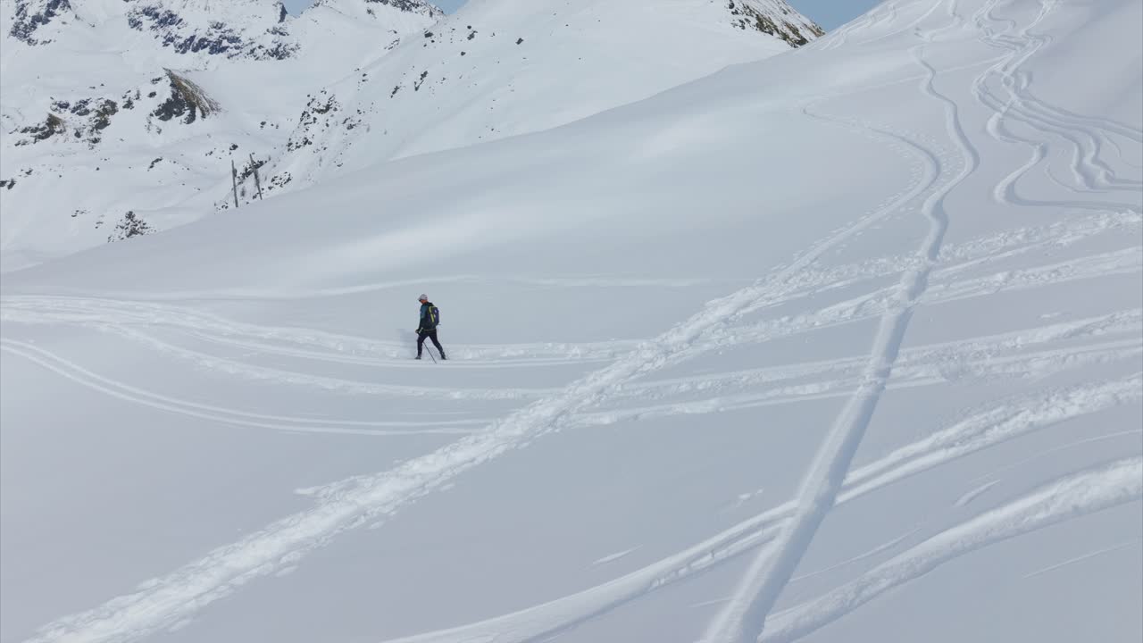Snowshoer across vast snowy mountain landscape, Alps scenery, winter sports, copy space. Aerial drone, low flight