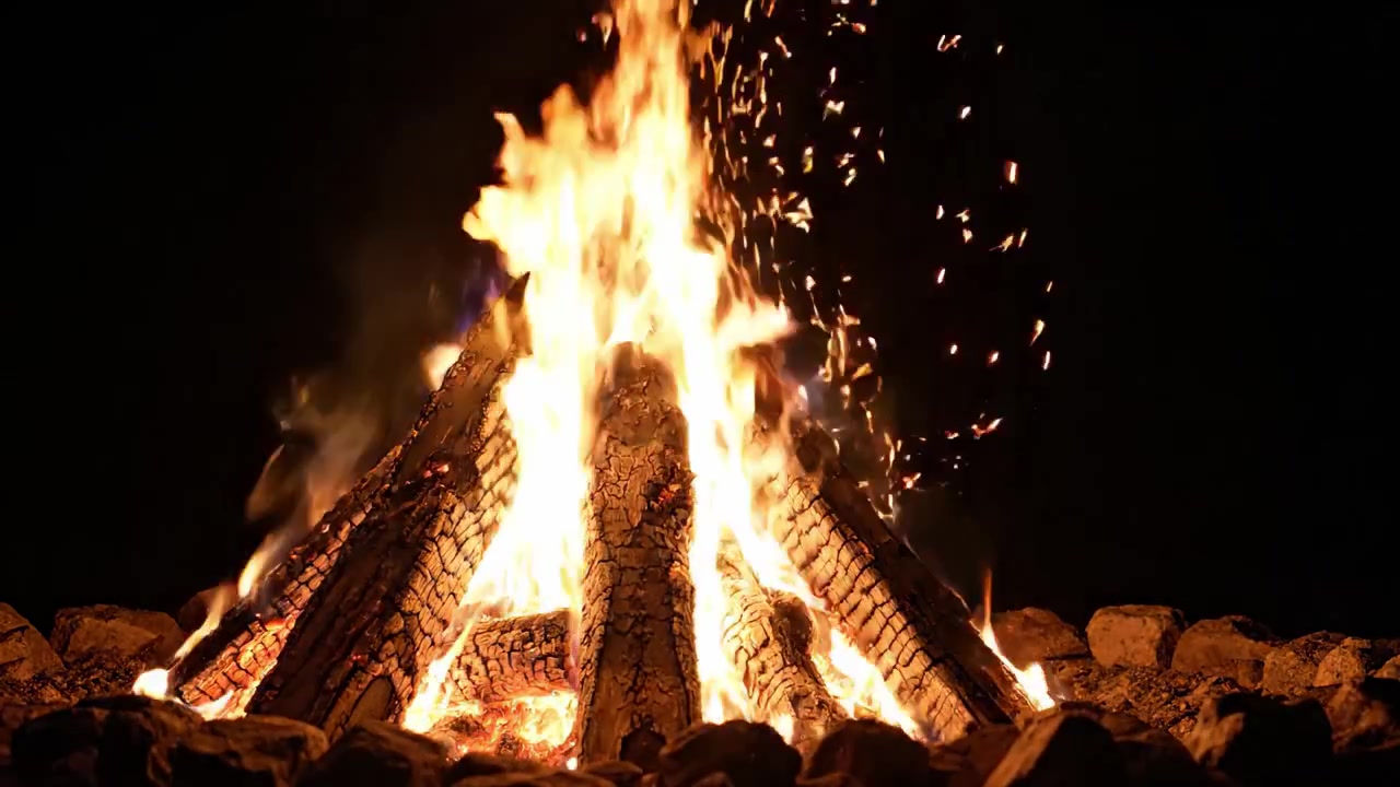 Un fuego hipnotizante ardiendo en la oscuridad, con llamas brillantes bailando y chispas volando, iluminando la noche y creando una atmósfera cálida y acogedora.