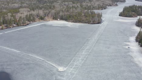 Círculo-Aéreo-Dejado-Sobre-El-Lago-Congelado-Derritiéndose-Con-Grietas-En-Los-Caminos-De-Hielo-Aún-Visibles-En-Canadá