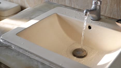 water running in a beige sink