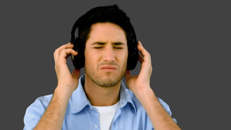 man listening to music with headphones on grey background