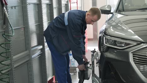 mechanic performing a wheel alignment process in a modern workshop. professional equipment is used to ensure accurate vehicle alignment for optimal performance and safety