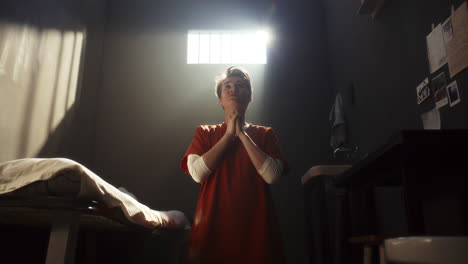 female inmate begging god for forgiveness during prayer in prison cell