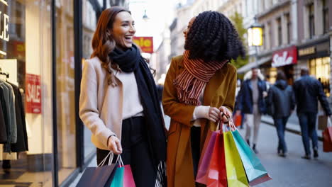 two happy women shopping on a city street