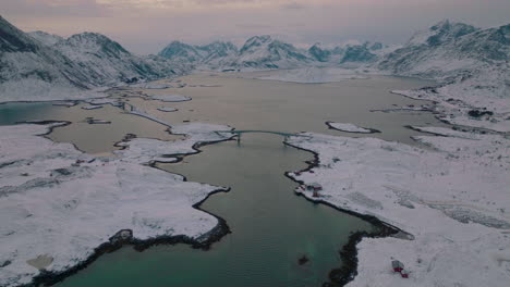 vista aérea sobre ramberg village nordland hielo congelado fiordo lago y montañas panorámicas, escandinavia