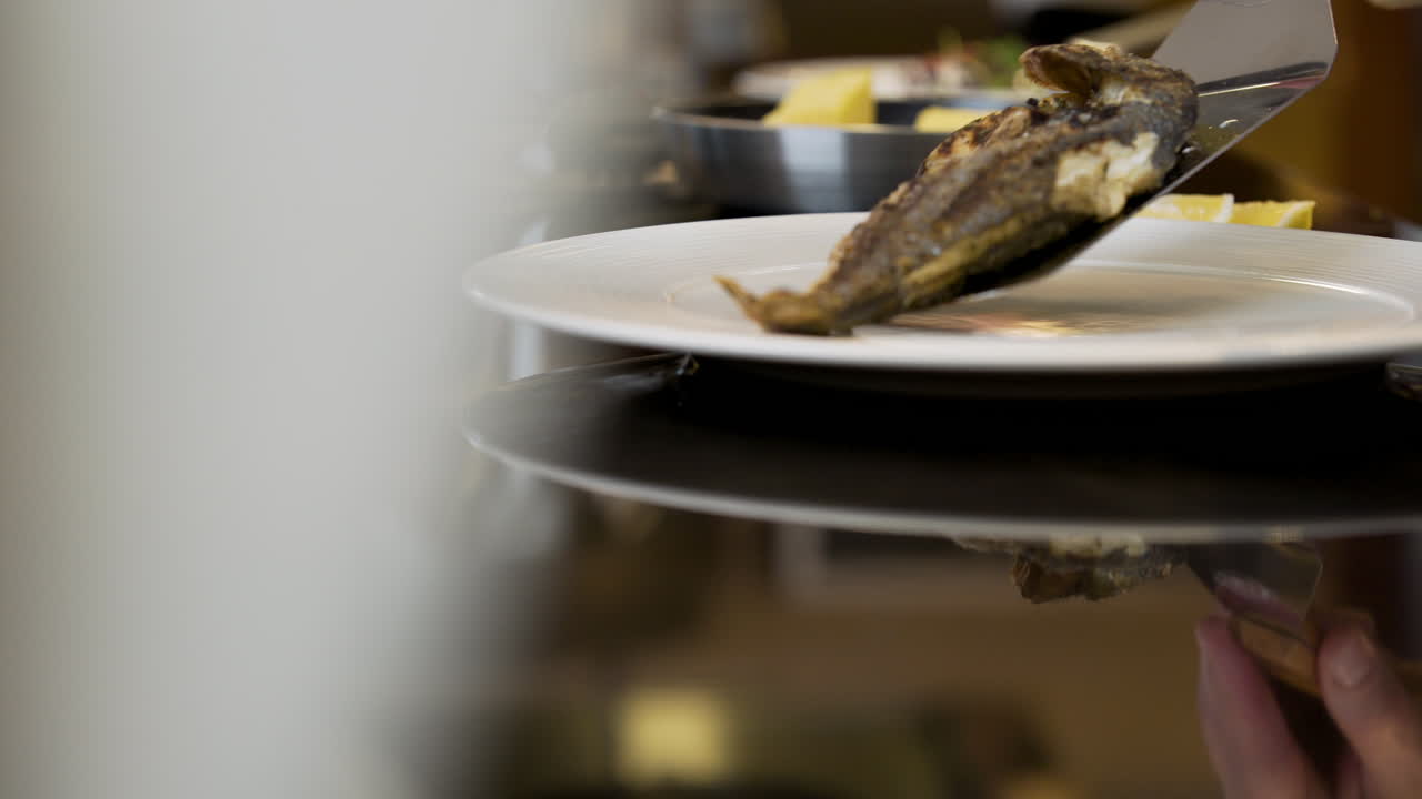 주방장이 구운 생선을 접시에 담고 있다