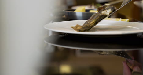 el chef está poniendo pescado a la parrilla en un plato