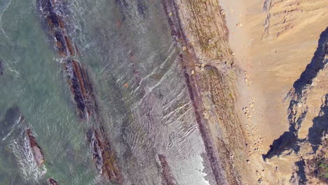 straight down aerial view of the waves washing ashore at rca beach in central california along the sandstone cliffs