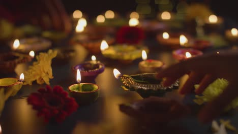 primer plano de manos encendiendo lámparas de aceite diya celebrando el festival de diwali en la mesa oscura 1