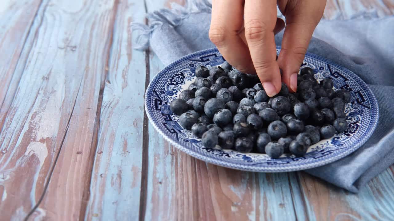 빈티지 접시 에서 블루베리 를 손 으로 뽑는 것