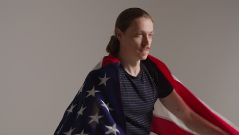 studio portrait shot of man wrapped in american flag celebrating 4th july independence day 3