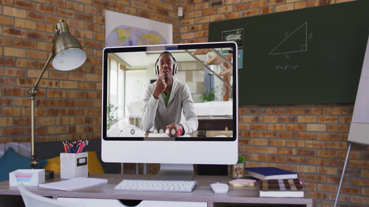 Webcam view of african american male college student on video call on computer on table at school