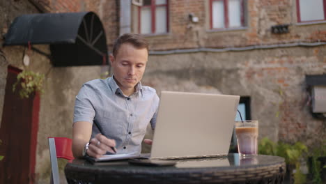 smiling man with works from home in his kitchen using a laptop. remote work and remote learning. remote work during self-isolation in quarantine man works with financial documents.