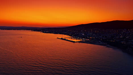 Orange sky reflects in the waterscape of the Black Sea near the shore of Bulgaria. Dusk time in the resort city. Aerial view